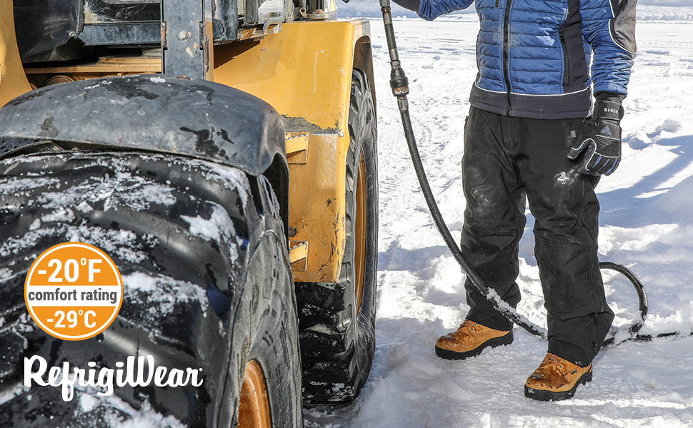 Man standing next to a tractor in the snow wearing RefrigiWear Insulated Softshell Pants